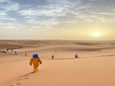Travelers riding camels over desert dunes
